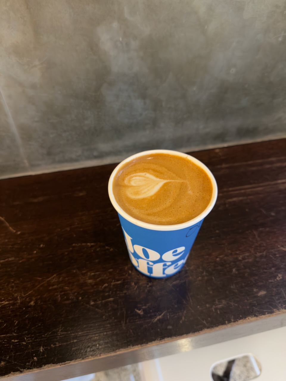 A cafe latte from Joe Coffee on a dark wooden counter